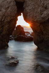 Sunstar in a sea cave in Malibu at sunset