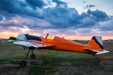 Fototapeta na wymiar Orange sports airplane parked at the airfield at scenic sunset