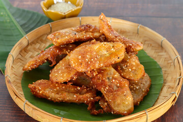 Fried banana fritters on the bamboo tray at close up view - Famous asian snack on wood table