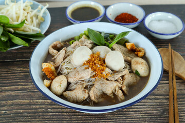 Thai style noodle soup served with vegetable at close up view on wood table - Famous street food, Thai boat noodle soup