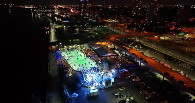 Aerial Of Ice Skating Rink At Penns Landing, Riverrink By Delware In Philadephia. Lights At Night With Urban City Philly Skyline.