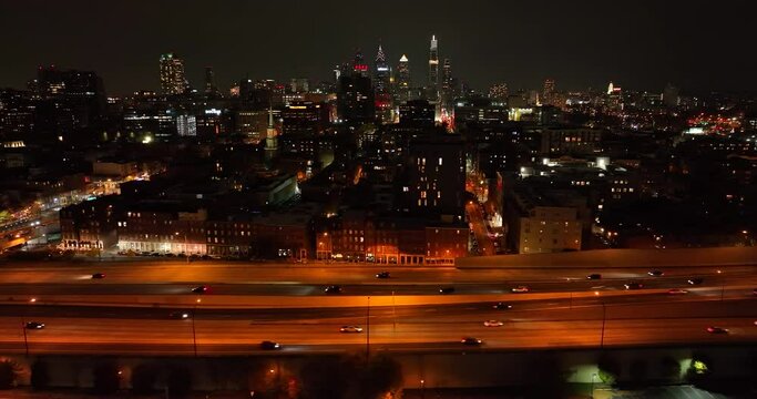Aerial truck shot of traffic at night on highway. Freeway expressway against dark sky and cityscape.