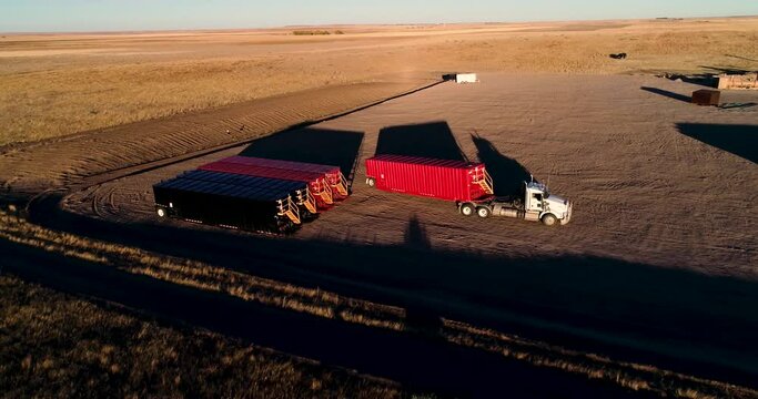 A semi truck is skillfully driven into place as a driver delivers a large piece of drilling equipment.  A drone 4K shot during sunset.