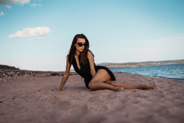 Fototapeta premium a young woman in a black dress lies on the sand. High quality photo