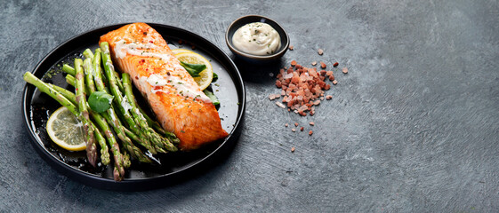 Baked salmon with asparagus on gray background.
