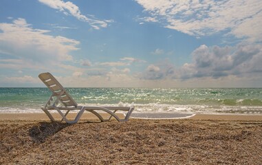 Empty white plastic deck chair by the sea. Summer vacation travel concept