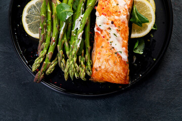 Baked salmon with asparagus on gray background.