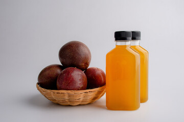 Fresh passion fruit juice in in plastic bottles with passion fruits on white background.