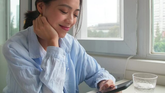 Side view Happy Asian young girl looking at mobile phone smiling young people using smart phone browsing online