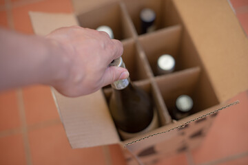 Hand seen removing wine bottle from box