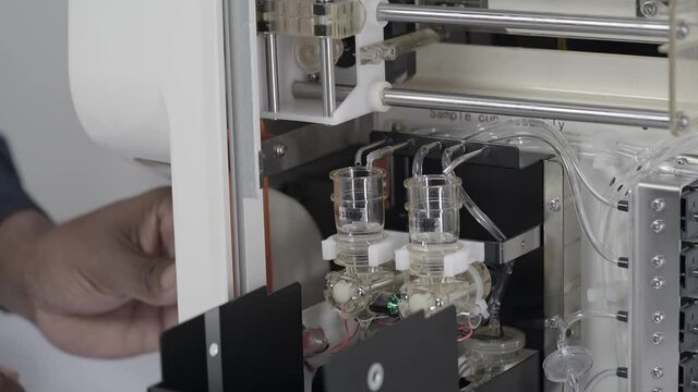 Hand putting blood sample into Blood CBC machine. Open equipment. Static
