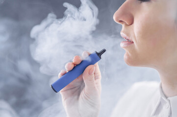 Caucasian woman smokes a disposable vape in the studio.