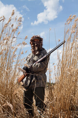 a masked hunter stands among the reeds