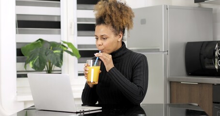 Black woman wears headset conference calling on laptop talks with online teacher studying, working from home. African american woman e learning using computer webcam chat makes notes. 