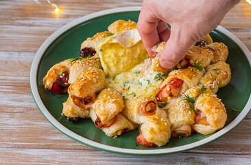 Step by step cooking of baked camembert in puff pastry with bacon, date and apple on a wooden plate. Recipes for holiday snacks. Step four, the finished dish.
