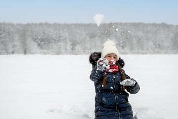 Fototapeta na wymiar Beautiful happy girl playing snowballs, laughing and having fun with snow