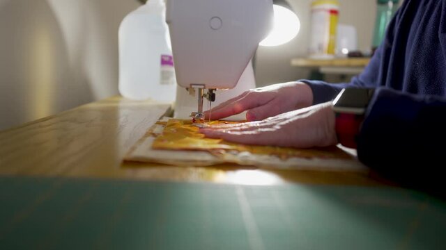 Skilled homemaker sewing quilt block scraps together on a machine - ORANGE SCRAPS SERIES
