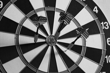 Concept of competition and goal achievement.Achieving goals in business and life.Dartboard with three darts stuck right center of target,on a black and white photo.