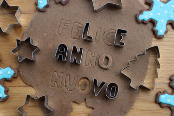 Felice anno nuovo . Gingerbread Cookie dough letters on wooden table with festive cookie cutters and glazed cookies - obrazy, fototapety, plakaty