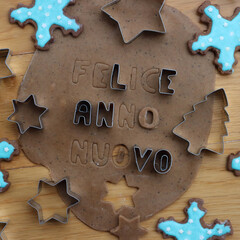 Felice anno nuovo . Gingerbread Cookie dough letters on wooden table with festive cookie cutters...
