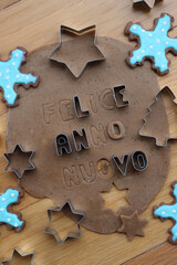Felice anno nuovo . Gingerbread Cookie dough letters on wooden table with festive cookie cutters...