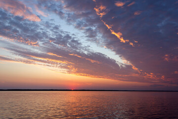 Dawn on the Volga River, the sun rises from the horizon and beautifully illuminates the clouds with...