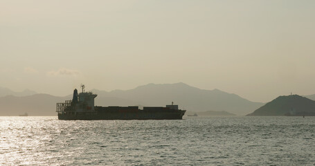 Fototapeta premium Cargo ship pass though the sea at sunset time