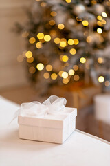 Gift box on background of New Years bokeh lights of Christmas tree.Copy space. Soft selective focus.