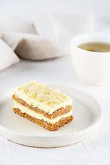 A piece of sliced ​​lemon cake with almonds and a cup of tea on the table. Sugar, gluten and lactose free and vegan.