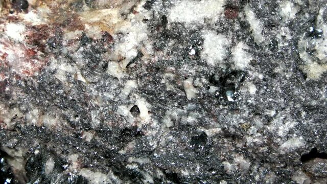 Macro of a quartz-biotite gneiss with quartzitic crystalline layers and zincblende inclusions in a dark rock matrix.