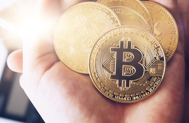 As a digital money cryptocurrency background, a hand holds a symbol of Bitcoins.