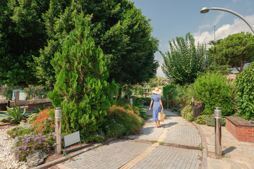A woman walks through the city botanical park among trees and exotic plants.