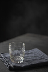 Empty glass on blue napkin on dark table.