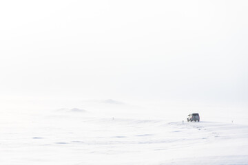 a lonely car drives on a snowy siberian road frost winter day in russia the jeep makes its way along the winter road