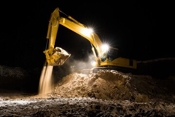 Tractor excavator worker digs a trench on a construction site at night - obrazy, fototapety, plakaty