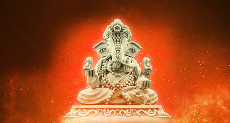 Selective focus on statue of Lord Ganesha, Ganesha Festival. Hindu religion and Indian celebration of Diwali festival concept on dark, red, yellow background.