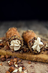 Cannoli, deep fried Italian pastry tubes with a sweet ricotta cheese, chocolate chips and hazelnuts served on a wooden board
