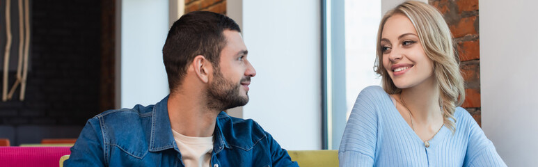 Obraz premium happy young couple looking at each other while spending time in cafe, banner