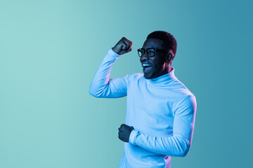 Studio shot of young fashionable guy, student wearing white neck-polo and jeans isolated on blue background in neon light. - obrazy, fototapety, plakaty