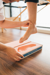 Fototapeta premium Chiropodist taking the shape of a patient's foot with a foam mold for the manufacture of a special insole.