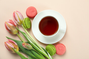 Obraz na płótnie Canvas Tea, tulips and macaroons on beige background