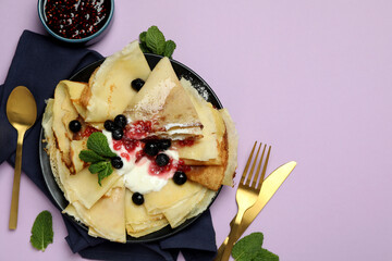 Concept of tasty food with crepes on violet background