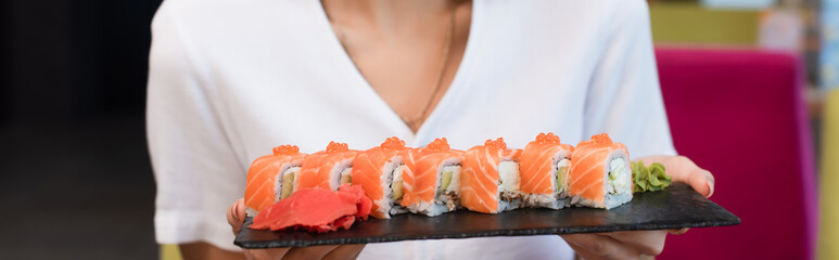 cropped view of woman with delicious sushi rolls, banner