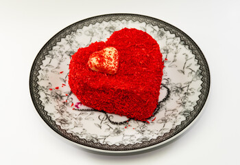 Heart shaped cake with red decoration in black and white porcelain plate on white background