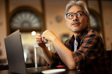 Businessman working on laptop in cafe. Handsome senior man enjoying in fresh coffee.