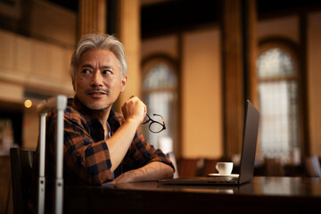 Businessman working on laptop in cafe. Handsome senior man enjoying in fresh coffee.