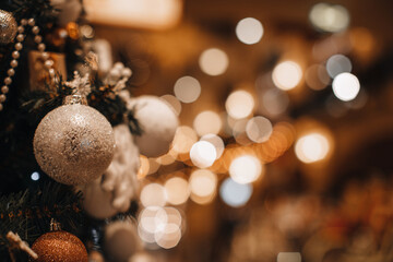 Christmas ball with silver glitter hanging on the Christmas tree branches. Winter holiday fairy garlands illumination and festive magic details in the interior
