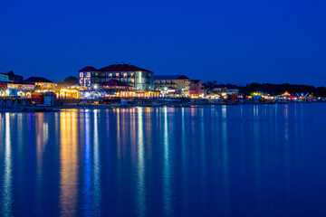 Fototapeta na wymiar Night lights on the sea shoreline. Resort town view from the sea to the shore.