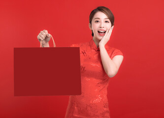 Happy chinese new year. Excited Asian young Woman showing gift and holding  the shopping bag
