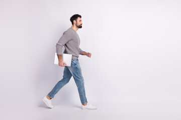 Naklejka premium Full body profile side photo of young man walk hold laptop representative isolated over grey color background